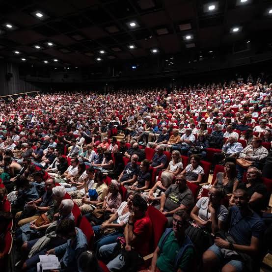 A packed red-seat auditorium during a festival screening